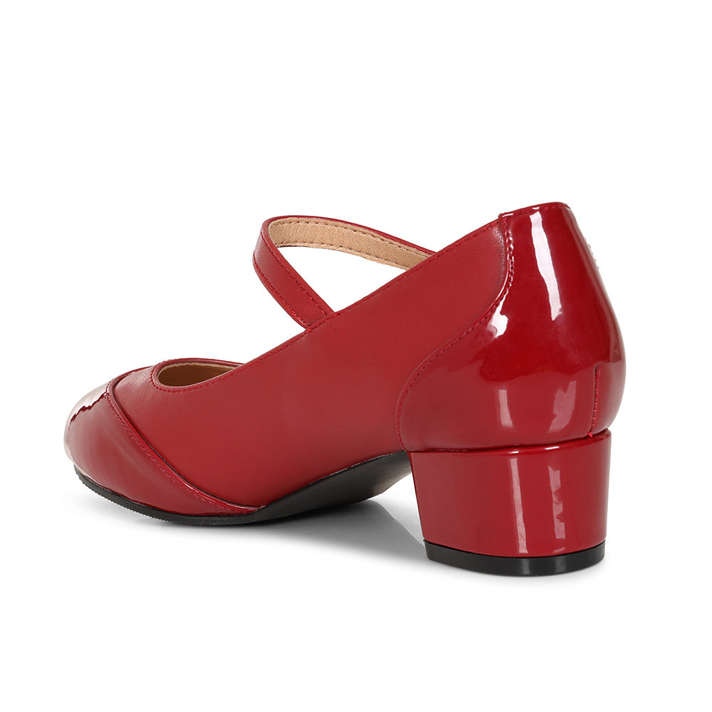 A red patent leather Mary Jane shoe with a low block heel, shown from a side-rear angle on a white background.
