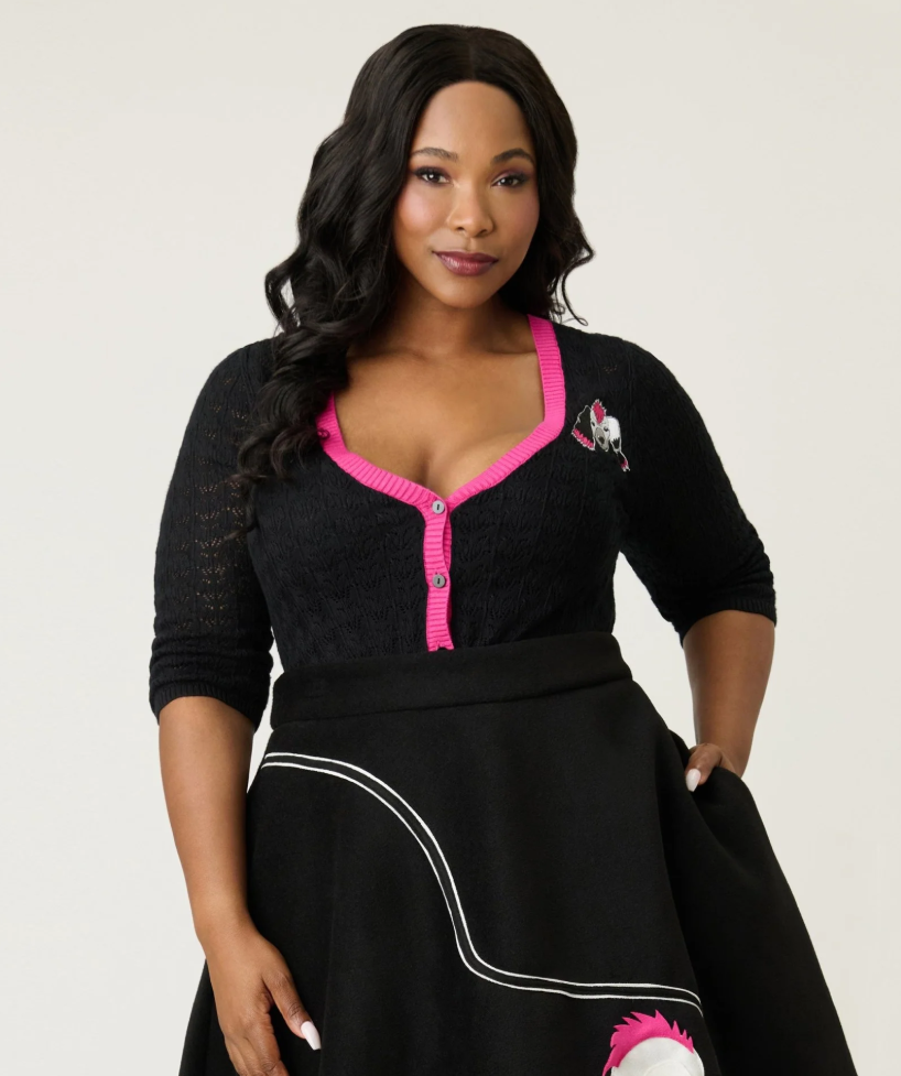 Woman wearing a black dress with pink accents against a plain background