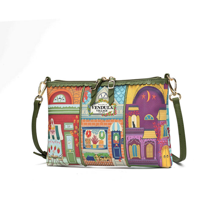 A multicolor crossbody bag featuring a vibrant, whimsical storefront illustration pattern. The bag has an olive green strap, gold-tone hardware, and a central metal plaque that reads 'VENDULA VILLAGE'.