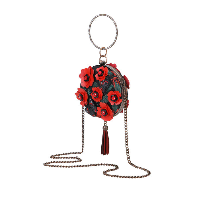 Round handbag with red floral design and chain strap on a white background