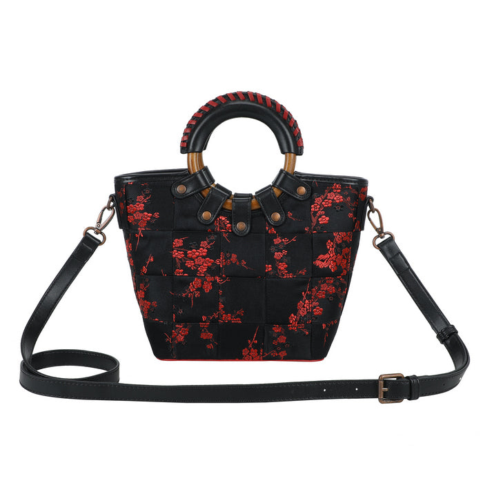 Black handbag with red floral pattern and wooden handle on a white background