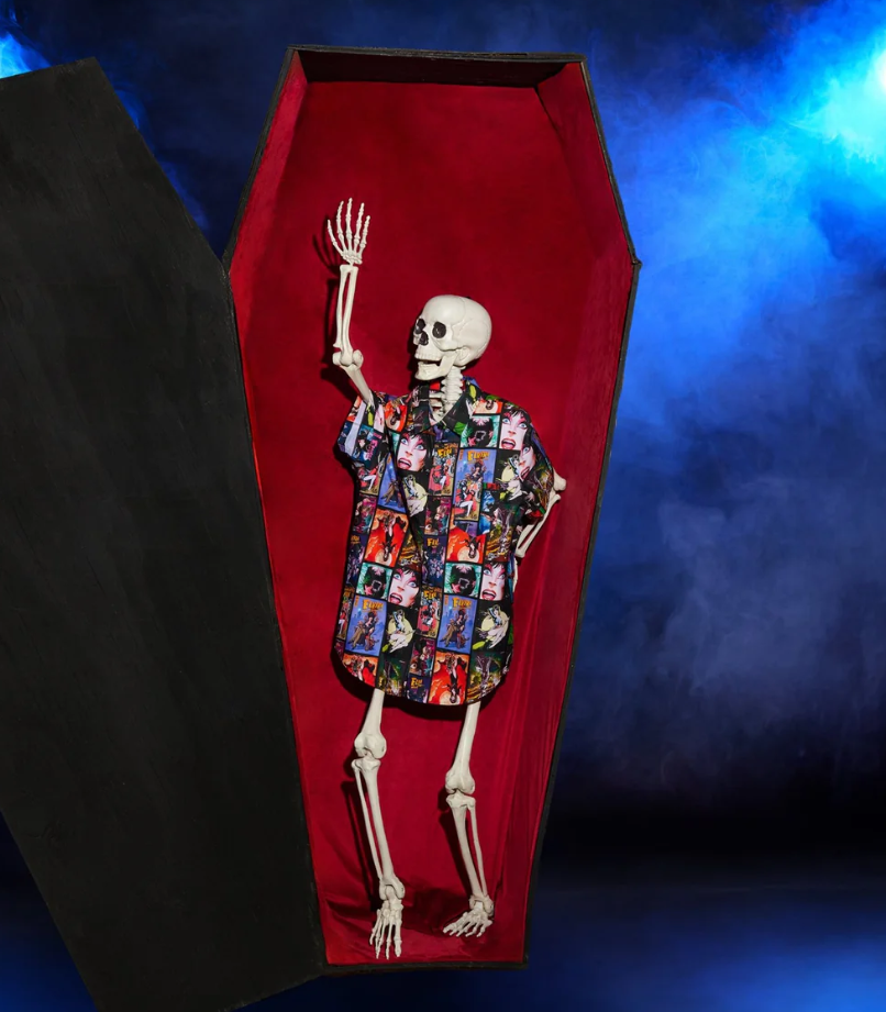 Coffin with a skeleton wearing a patterned shirt against a dark background