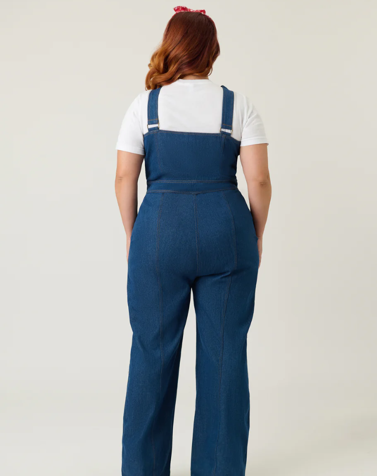 Person wearing blue denim overalls on a plain background