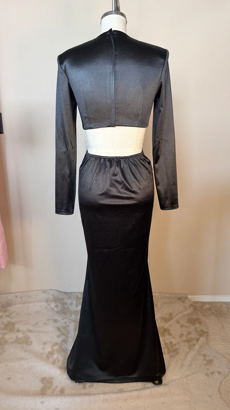 Black evening gown with sheer long sleeves on a mannequin against a neutral background