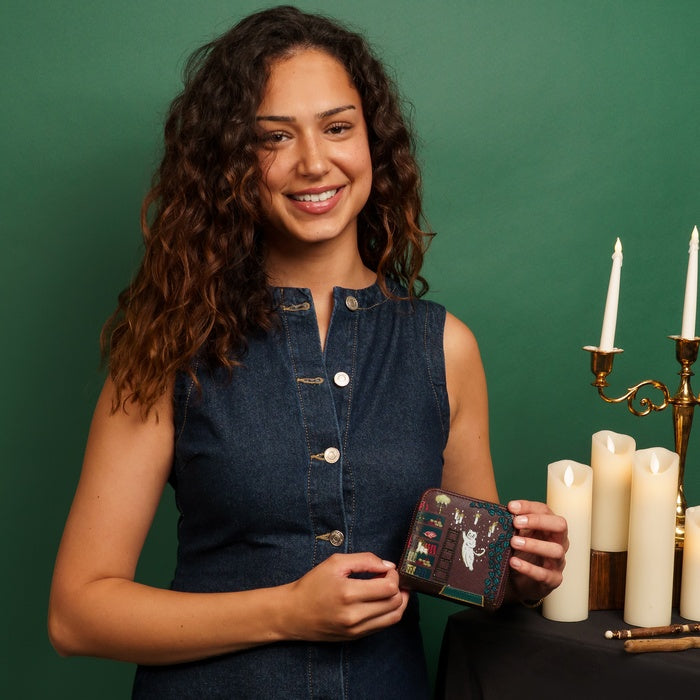 Woman holding a small wallet with candles and a candelabrum in the background