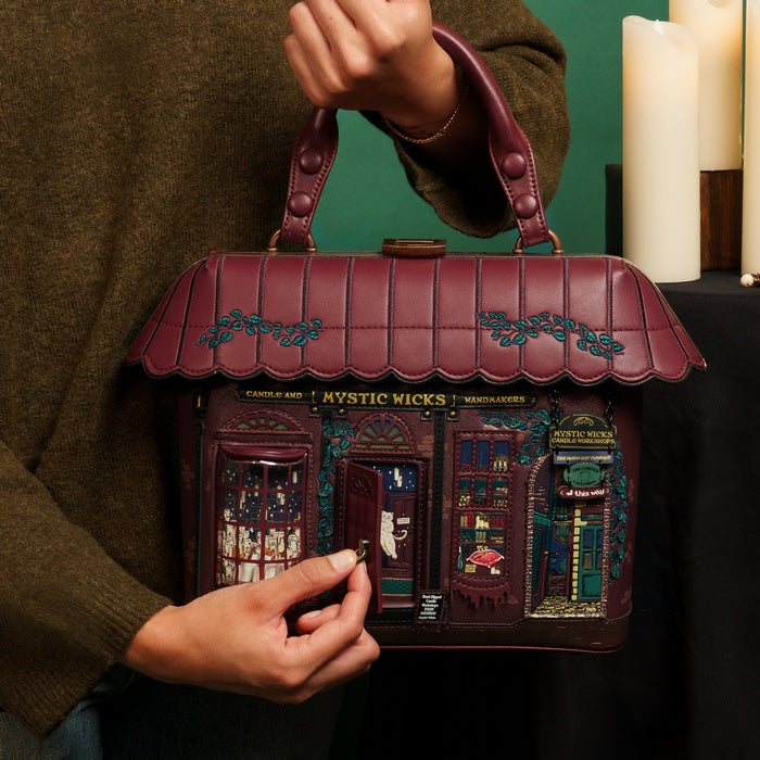 Handbag designed like a store facade with 'Mystic Wicks' branding, held by a person.