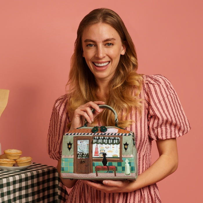 Woman holding a handbag with a vintage store design against a pink background