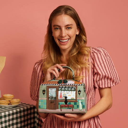 Woman holding a handbag with a vintage store design against a pink background
