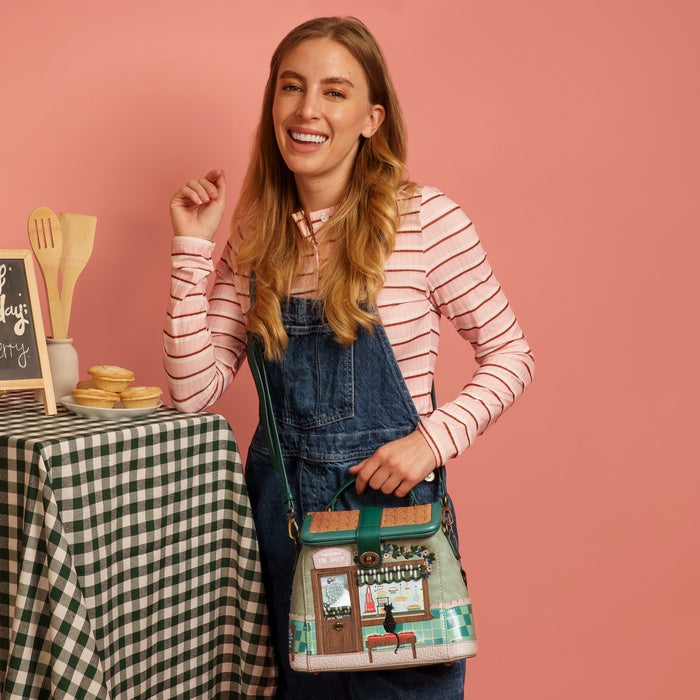 Woman holding a colorful bag with a checkered tablecloth and chalkboard in the background