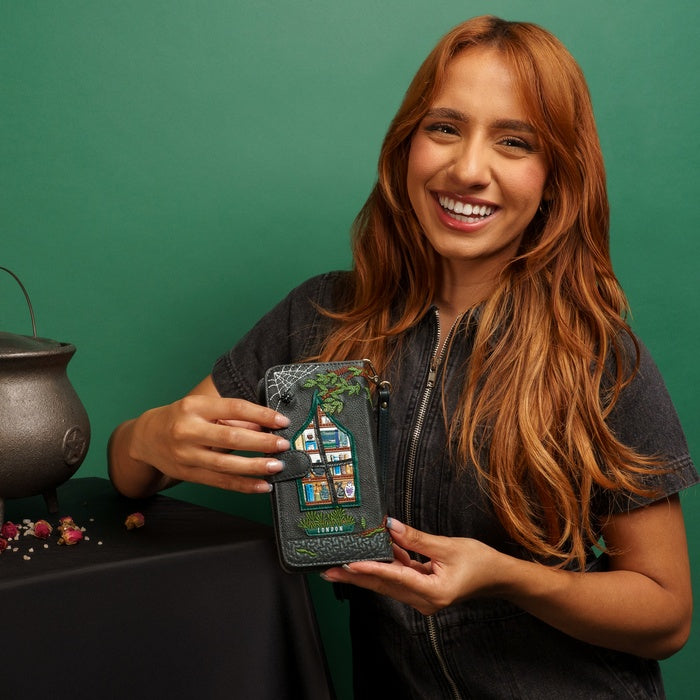 Woman holding a phone case with a house design against a green background