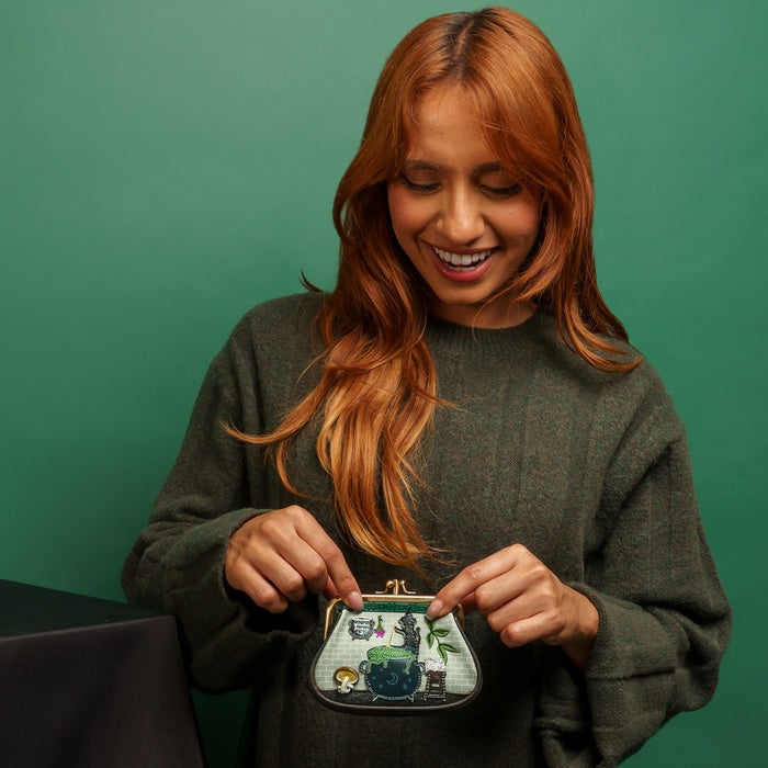 Woman holding a small handbag with a detailed design against a green background