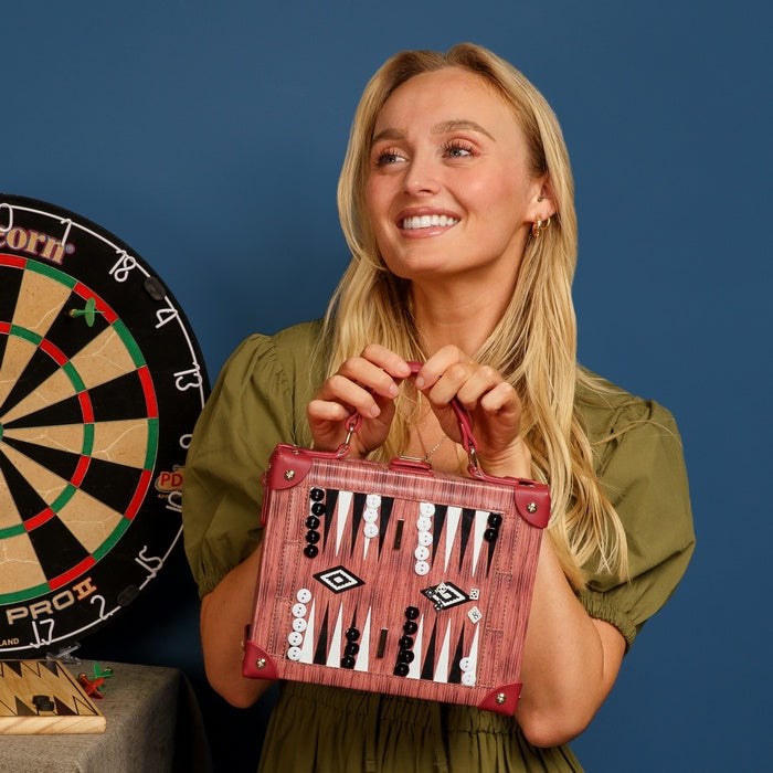 Woman holding a backgammon set with a dartboard in the background