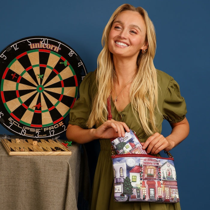 Woman holding a colorful bag with a building design next to a dartboard on a blue background