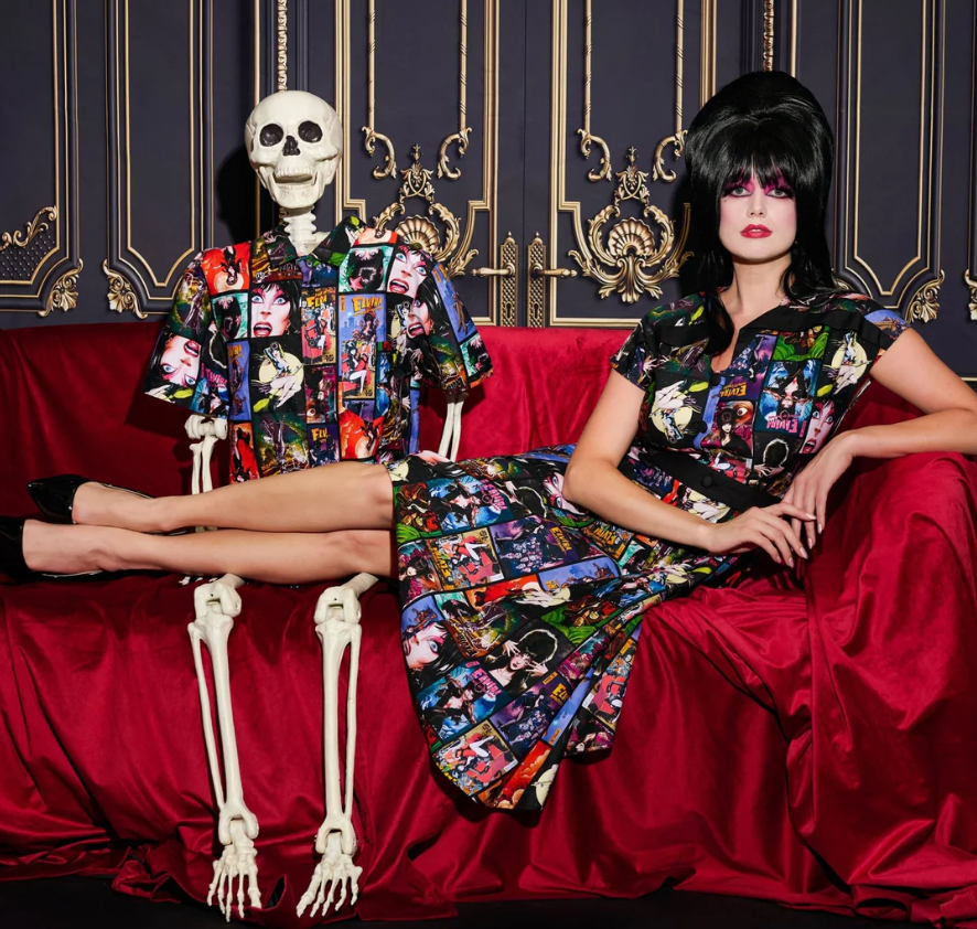 Person in a colorful dress sitting on a red couch with a skeleton next to them against an ornate wall.