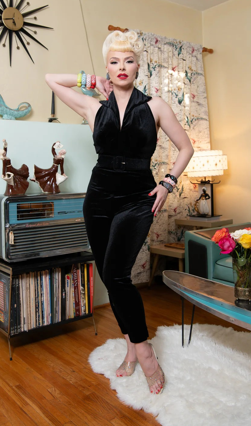 Woman in a black outfit posing in a room with vintage decor