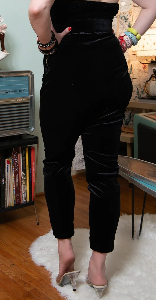 Person wearing a black outfit with high-waisted pants in a room setting.