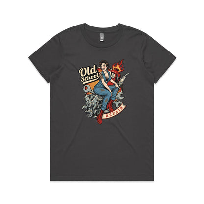 A vintage-style pin-up illustration printed on a white garment, showing a woman in blue overalls and red boots sitting on a motorcycle engine with wrenches, a gas pump, flames, and the words 'Old School' and 'REPAIR'.