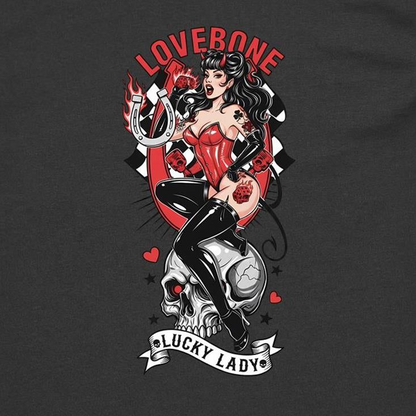 A dark charcoal gray t-shirt featuring a large graphic print of a pin-up style woman labeled 'LOVEBONE' and 'LUCKY LADY', seated on a skull with red, black, white, and gray details.