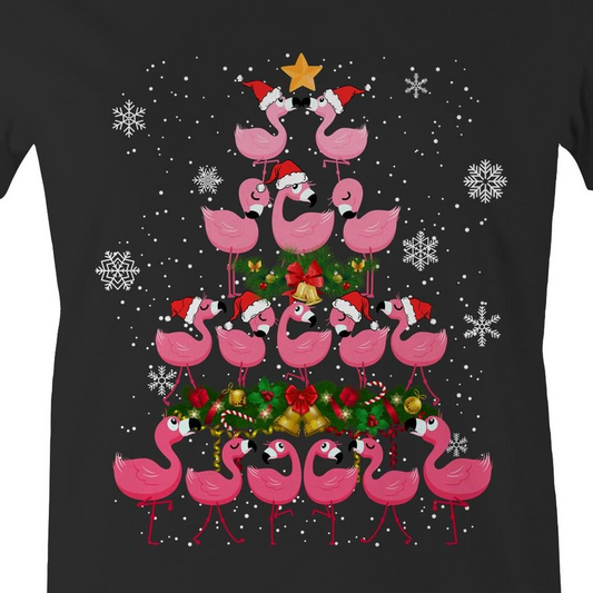 A black t-shirt featuring a festive Christmas graphic of pink flamingos stacked in the shape of a Christmas tree, wearing red Santa hats, with a green wreath, gold bells, and white snowflakes on a black background.