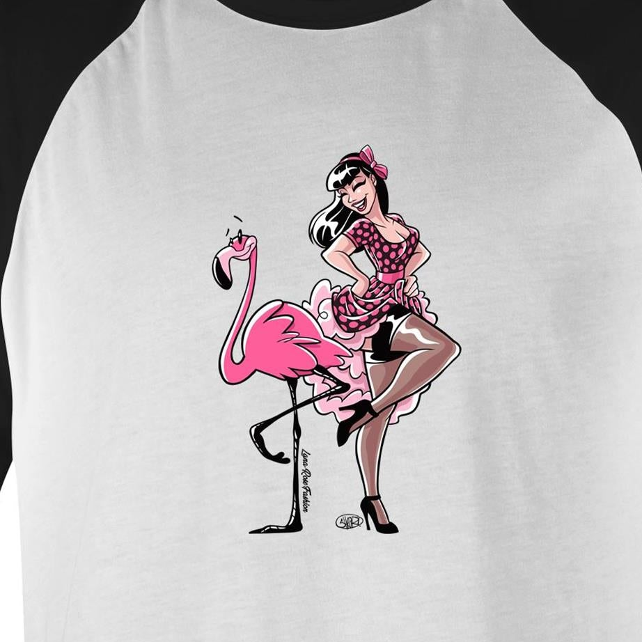 A white raglan baseball t-shirt featuring a retro-style graphic of a pin-up girl sitting on a pink flamingo. The shirt has black raglan sleeves and a black collar, with the graphic printed on the front.