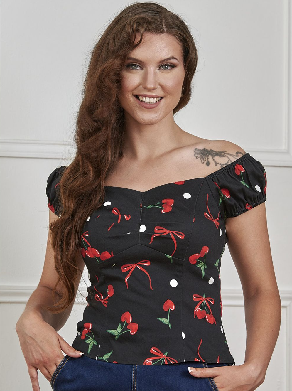 Woman wearing a black top with red and green designs against a white background