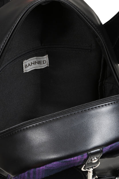 Close-up of the interior of a black bag, showing a black fabric lining with a white label that reads 'BANNED'. A purple patterned lining is visible along the bottom edge.