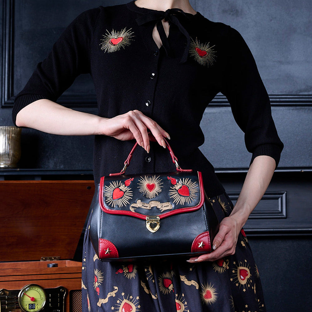 Woman holding a black handbag with red accents against a dark background