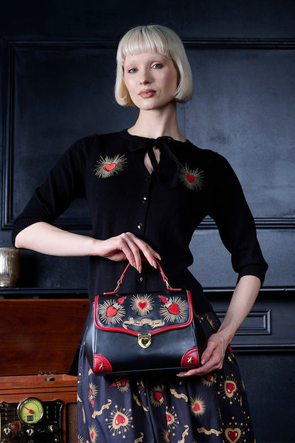 Woman holding a black handbag with red accents against a dark background