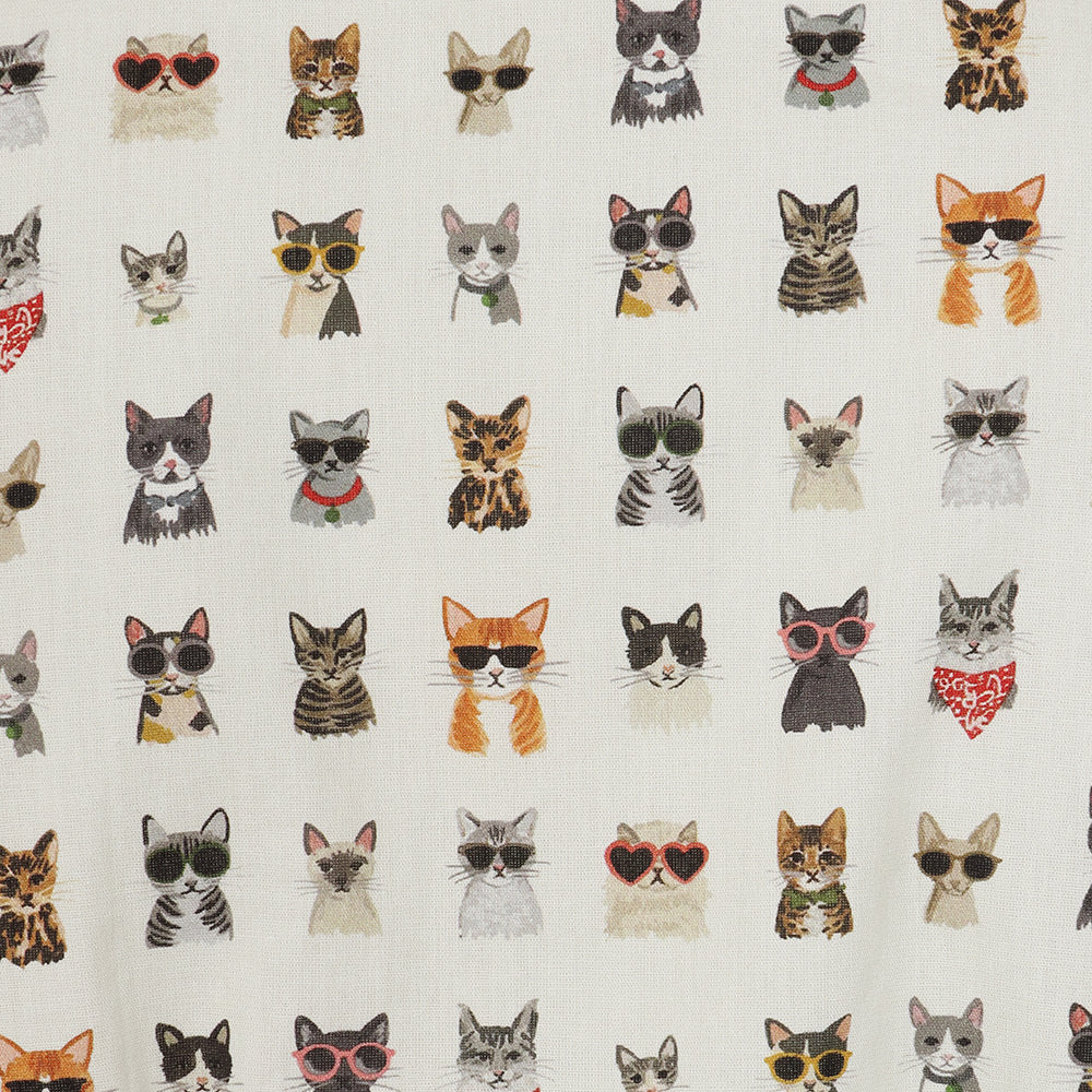 A close-up of a fabric surface featuring a repeating pattern of illustrated cats in various colors and styles of sunglasses and bandanas on an off-white background.