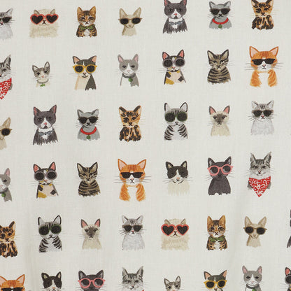 A close-up of a fabric surface featuring a repeating pattern of illustrated cats in various colors and styles of sunglasses and bandanas on an off-white background.