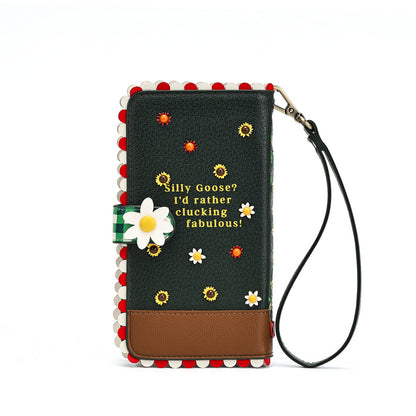 A long wallet-style phone case with a wrist strap, featuring a dark green textured front with embroidered daisies, yellow sunflowers, and gold text reading 'Silly Goose? I'd rather clucking fabulous!'. The case has red and white pom-pom trim, a brown lower panel, and a white daisy applique on the left side, shown on a plain white background.