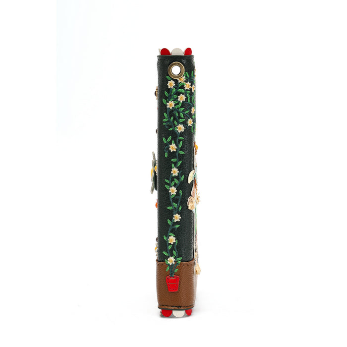A dark green leather cylindrical accessory, likely a strap or sleeve, decorated with a floral vine pattern, white embroidered flowers, a brown leather base, and red and white pom-pom details at the top and bottom, shown against a plain white background.