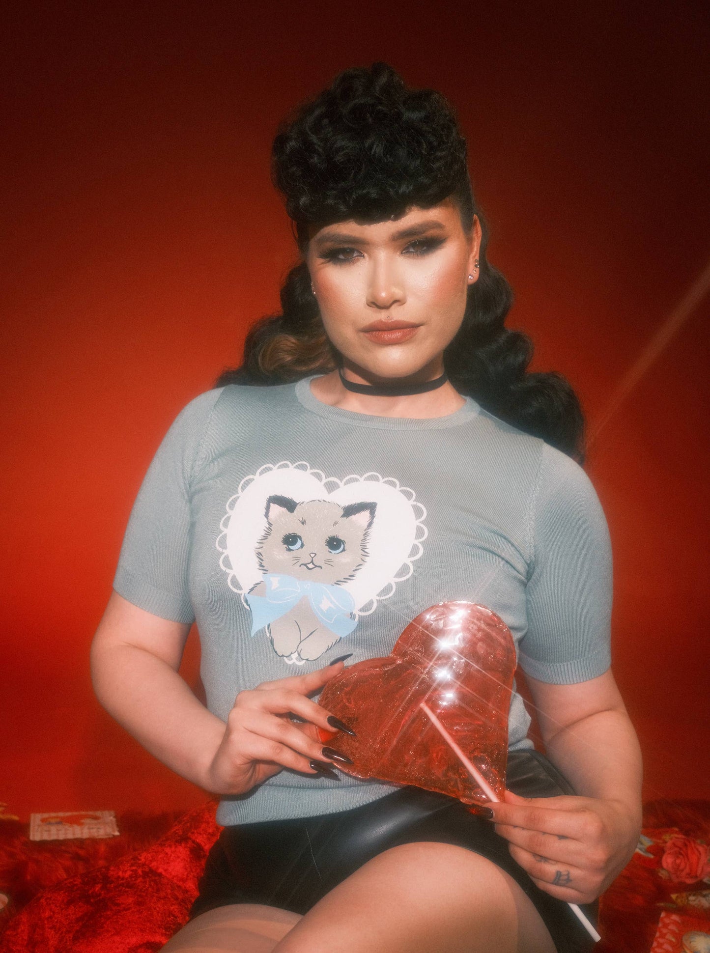 Woman wearing a t-shirt with a cat graphic against a red background
