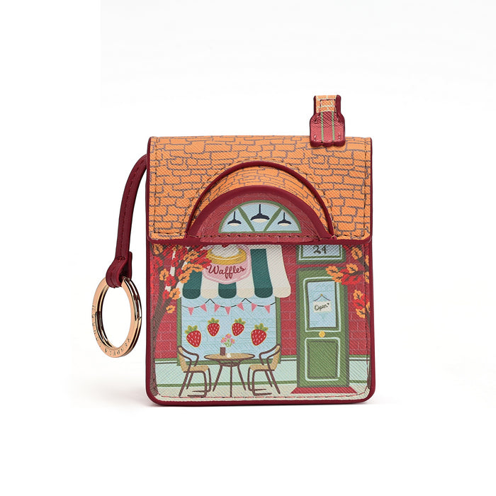 A small rectangular card holder or wallet with a house-shaped design, featuring an orange brick roof, red trim, and a colorful illustrated storefront scene with strawberries, tables, chairs, and a green door. A burgundy wrist strap with a gold-tone ring is attached on the left side, photographed against a plain white background.
