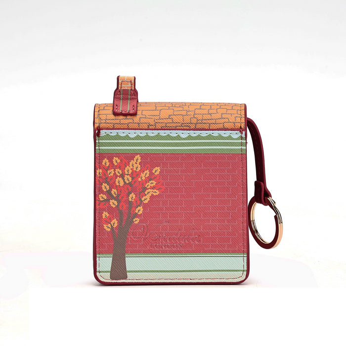 A small rectangular leather pouch with a top loop and attached wrist strap, featuring a red brick pattern, a tree with yellow-orange leaves, and horizontal green and light blue stripes on a white background.