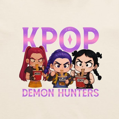 A graphic print featuring three chibi-style cartoon girls eating noodles, with the word 'K-POP' above them and 'DEMON HUNTERS' below, on a light cream background.