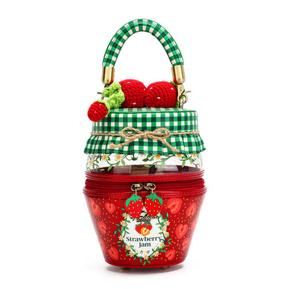 A novelty handbag designed to look like a strawberry jam jar, featuring a green and white gingham patterned handle, a green gingham lid with a twine bow, and a red body printed with strawberries and hearts. The front has a decorative label reading 'Strawberry Jam' with a gold zipper closure.
