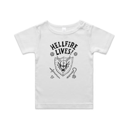 A close-up of a white garment, likely a t-shirt, featuring a black graphic print. The design displays the text 'HELLFIRE LIVES!' in a distressed, arched font above a horned skull inside a shield, surrounded by fantasy icons including dice, a sword, a key, and a gem.