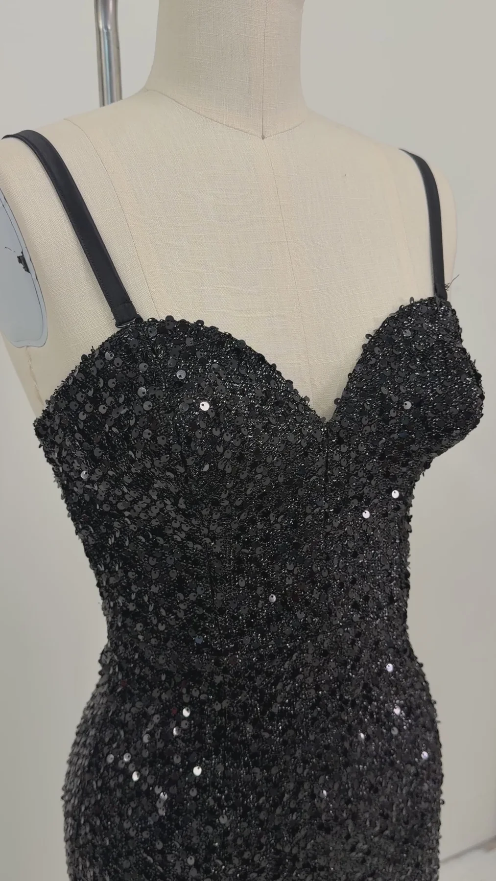 A black sequined strap dress displayed on a cream dress form mannequin against a plain light background.