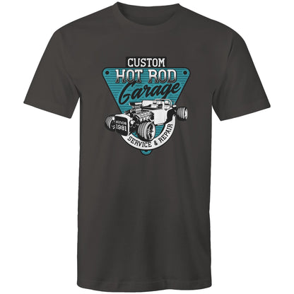 A light blue t-shirt featuring a large graphic print on the chest. The graphic is a teal and black triangular badge with the text 'CUSTOM HOT ROD Garage' and 'SERVICE & REPAIR since 1981', surrounding an illustration of a classic hot rod car with an exposed engine elements