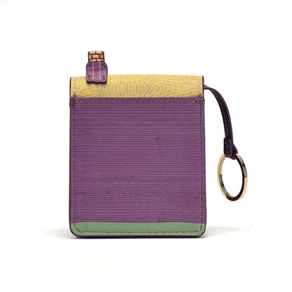 A small rectangular card holder or wallet with a textured finish, featuring a purple center, a yellow top flap, a green bottom trim, and a dark purple wrist strap with a gold-tone key ring.