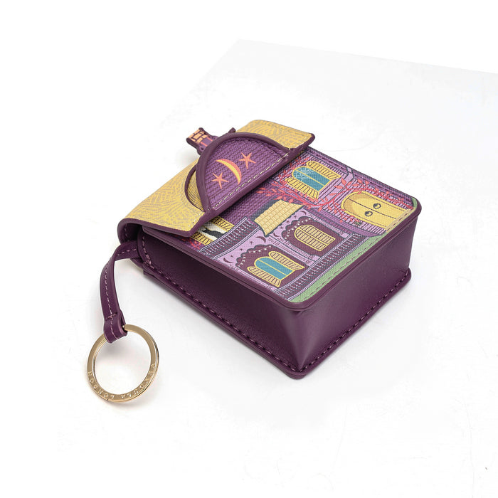 A small purple leather pouch with a decorative illustrated flap and a gold-tone key ring, photographed on a clean white background.