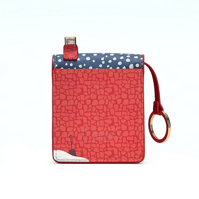 A small red textured card holder wallet with a navy blue top flap featuring white polka dots, a red leather loop tab, and a matching red wrist strap with a gold-tone ring, shown on a white background.