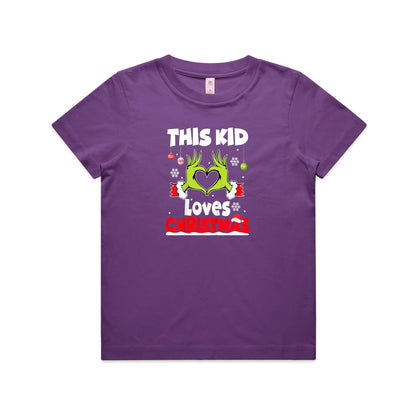 A close-up of a green Christmas t-shirt featuring a graphic of the Grinch's hands forming a heart, with the text 'THIS KID Loves CHRISTMAS' in white and red.
