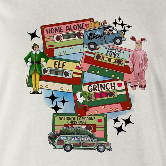 A graphic print on a light beige fabric featuring retro cassette tapes labeled 'Home Alone', 'Elf', 'The Grinch', 'National Lampoons Christmas', and 'A Christmas Story', with illustrated characters and black starbursts.