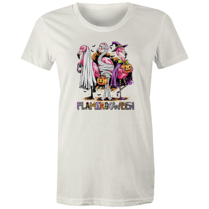 A white t-shirt featuring a colorful graphic of three cartoon flamingos dressed in Halloween costumes. One flamingo wears a white ghost and lantern, another is wrapped in bandages and holds a pumpkin bucket, and the third wears a purple witch hat and cape while holding a jack-o'-lantern.