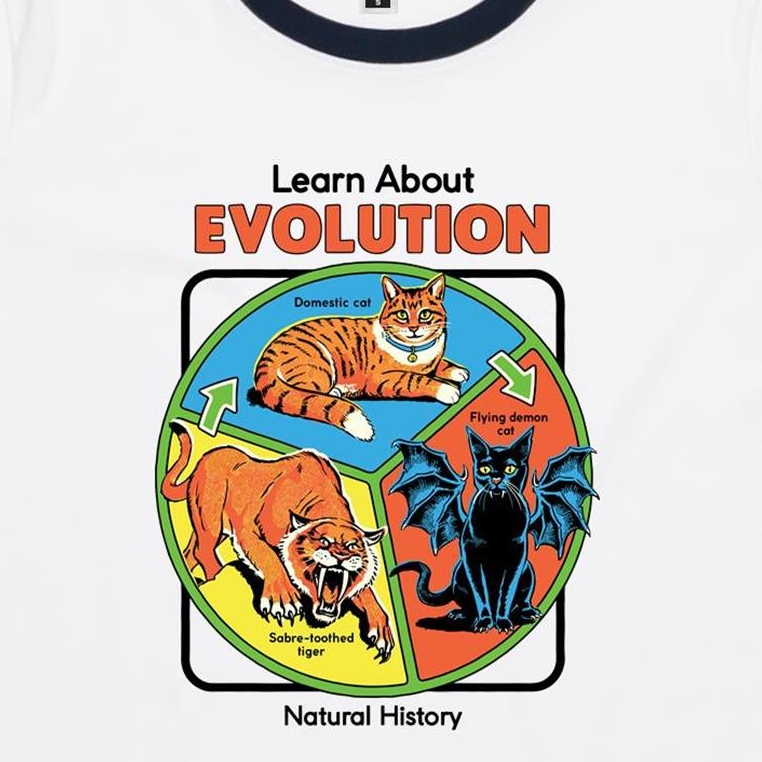 A white ringer t-shirt featuring a colorful educational graphic about evolution. The graphic shows a domestic cat, a flying demon cat, and a saber-toothed tiger arranged in a circle with the text 'Learn About EVOLUTION Natural History'.