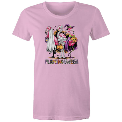 A white t-shirt featuring a colorful graphic of three cartoon flamingos dressed in Halloween costumes. One flamingo wears a white ghost and lantern, another is wrapped in bandages and holds a pumpkin bucket, and the third wears a purple witch hat and cape while holding a jack-o'-lantern.