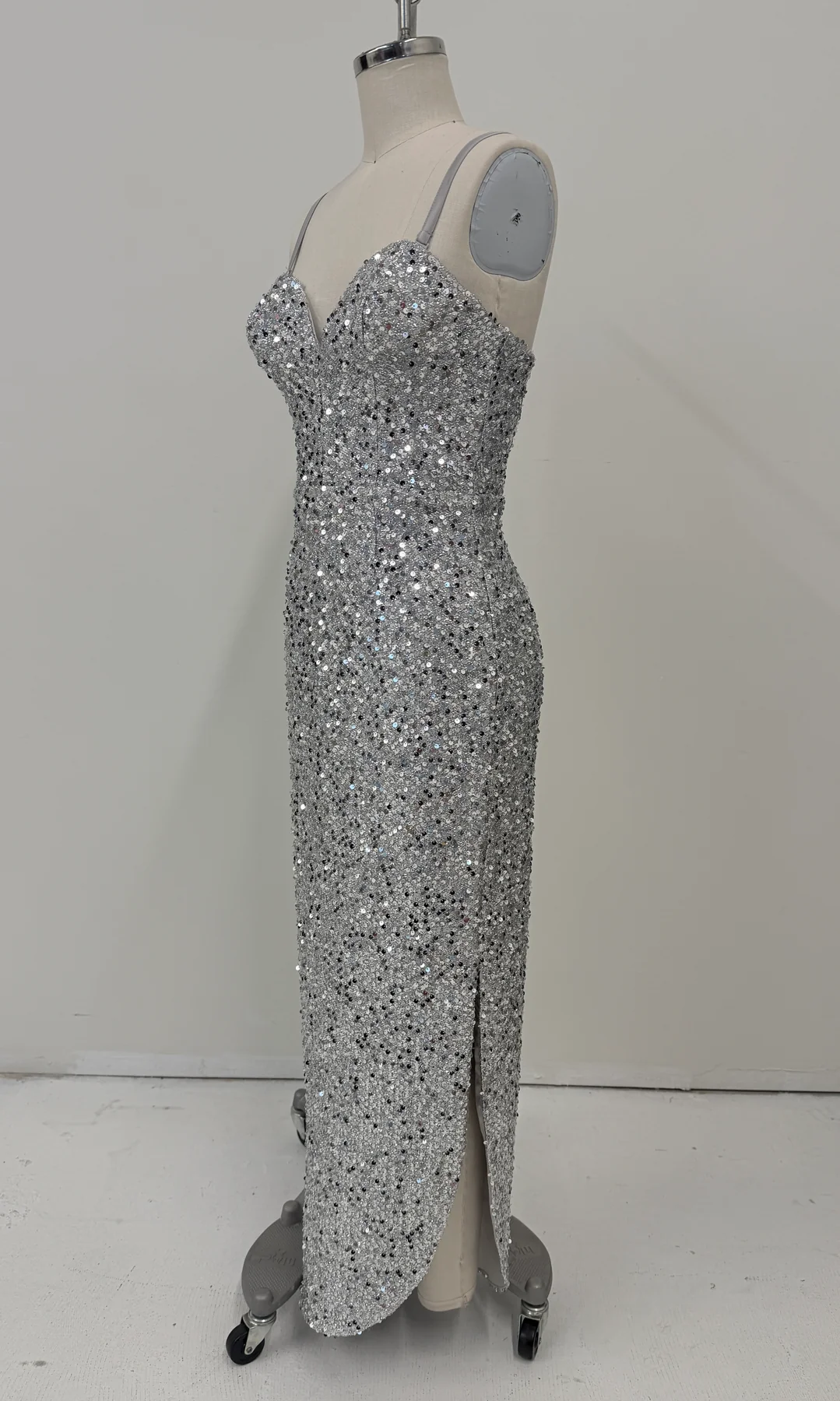 A floor-length silver sequin gown displayed on a dress form mannequin against a plain light gray studio background.