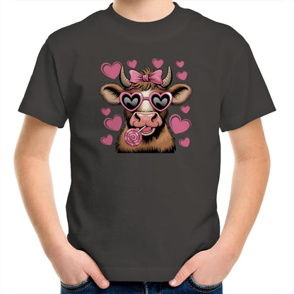 A stylized cartoon cow face with brown and cream fur, pink heart-shaped sunglasses, a pink bow on its horns, and a pink lollipop, surrounded by pink hearts on a light pink background.